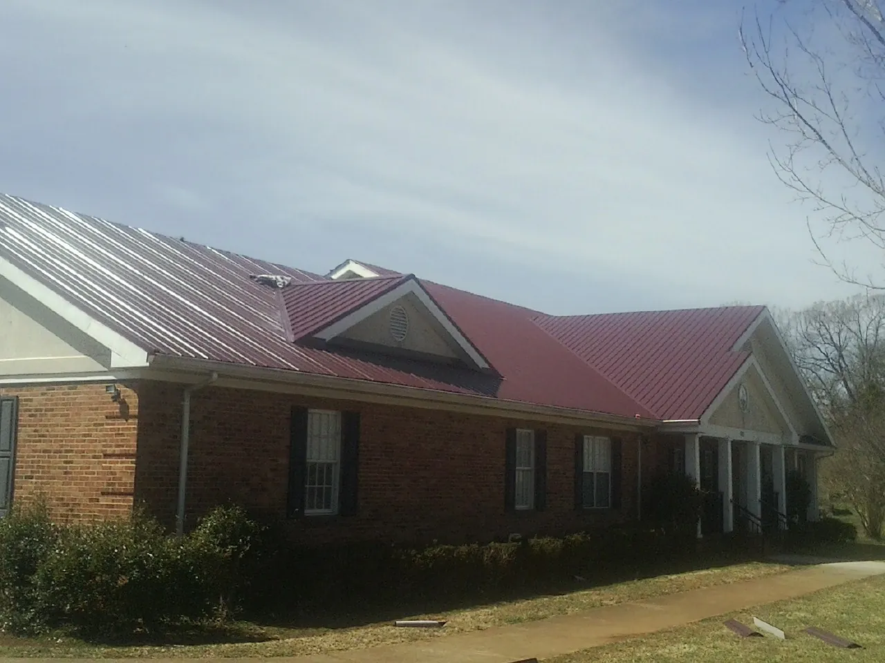 Red metal roof with gabled entries on a long brick building in Winterset