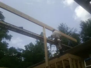 Carpenter setting a ridge beam over a new addition frame — Ice Dam Removal by Roofing Brothers in Winterset