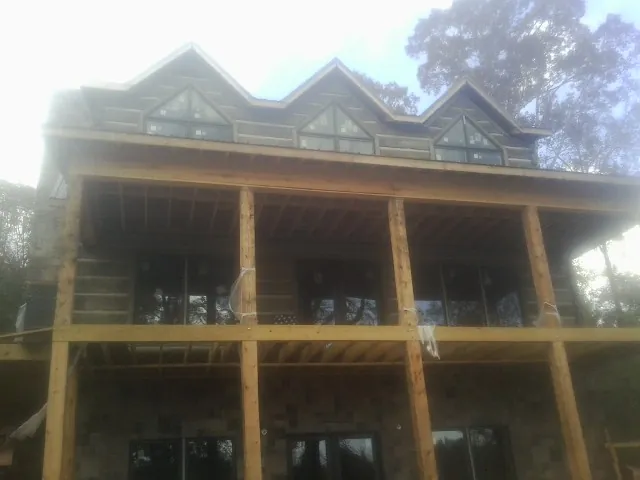 Dormers and porch framing on a large log home under construction — Roof Coating work by our crew in Winterset