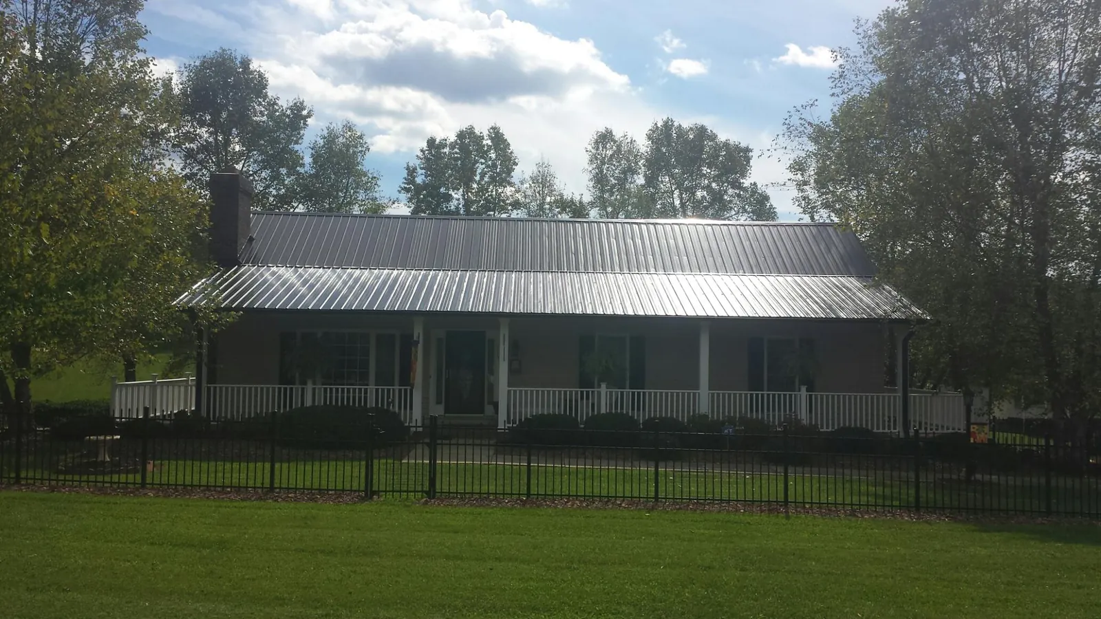 Gray metal roof on a brick ranch with a full width front porch — Gutter Guard Installation work by our crew in Winterset