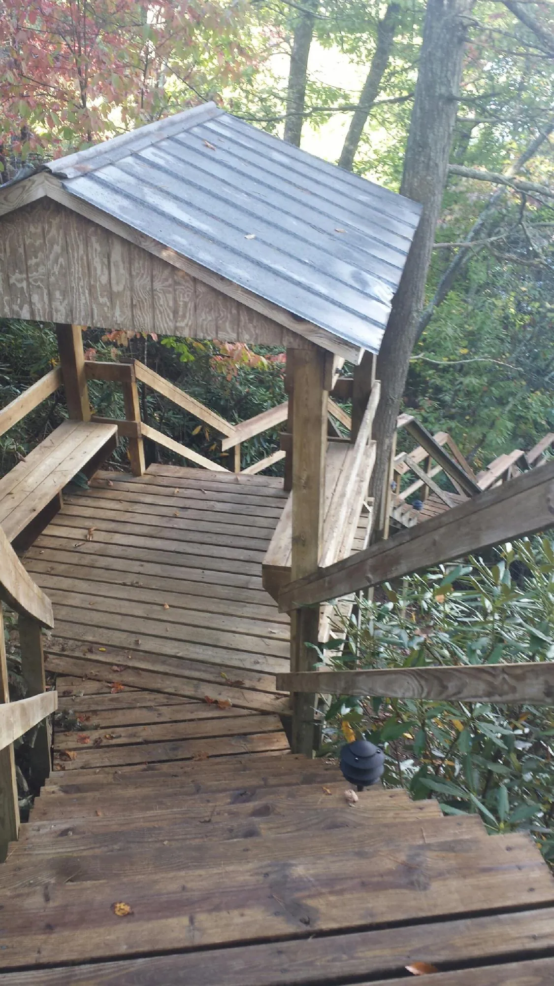Metal roofed shelter over wooden steps on a wooded walkway — Skylight Repair & Installation work by our crew in Winterset