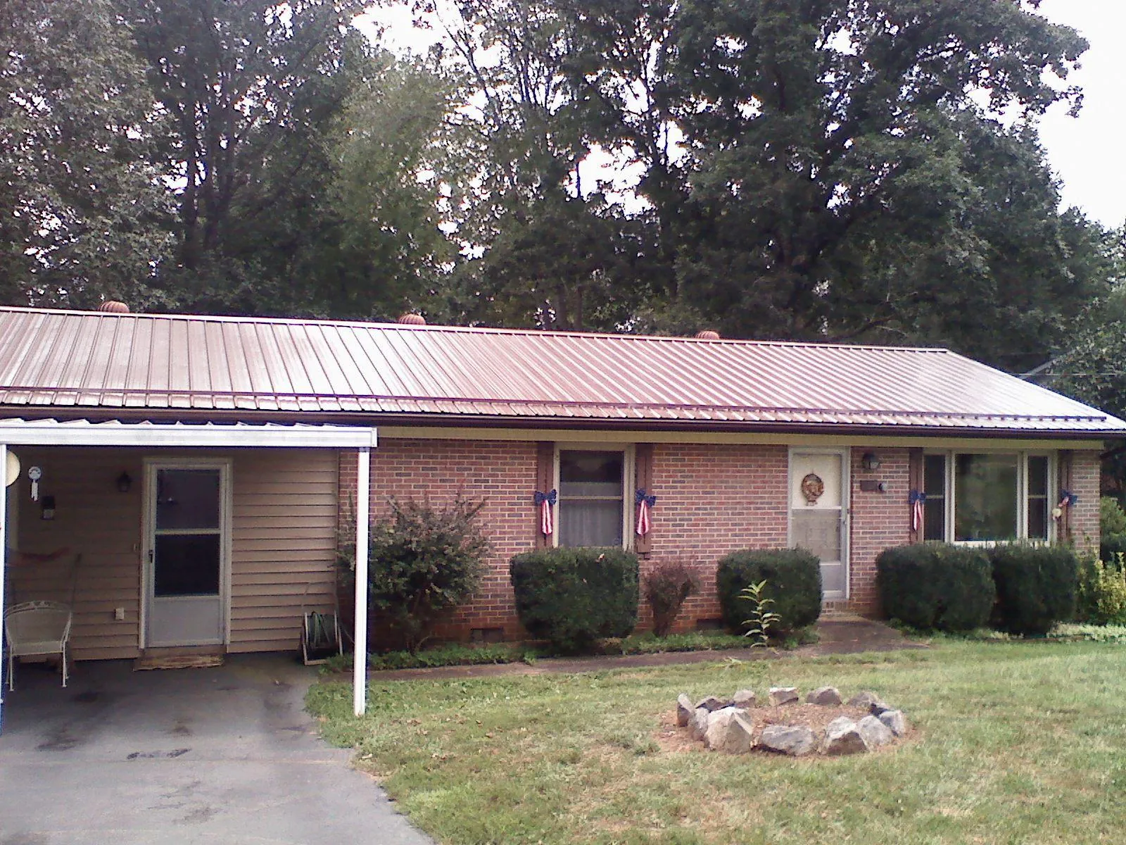 Bronze metal roof and carport on a brick ranch home — Roof Repair work by our crew in Winterset