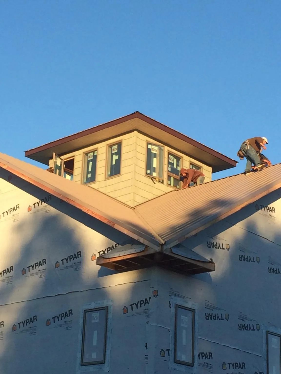 Roofers working around a rooftop cupola on a new metal roof at sunset — Roof Waterproofing in Winterset by Roofing Brothers